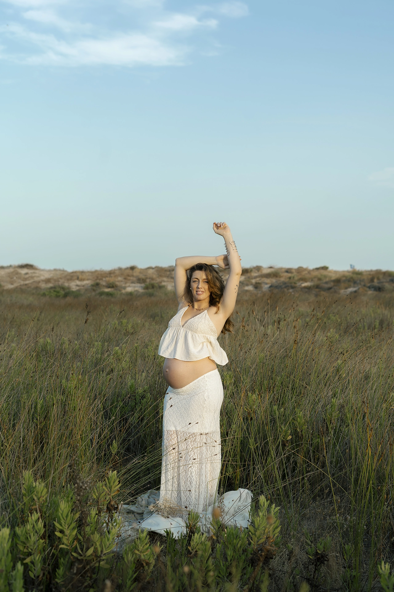Fotografia de mujer embarazada en exteriores, en el campo cerca de El Saler, valencia. sesión de fotos al atardecer