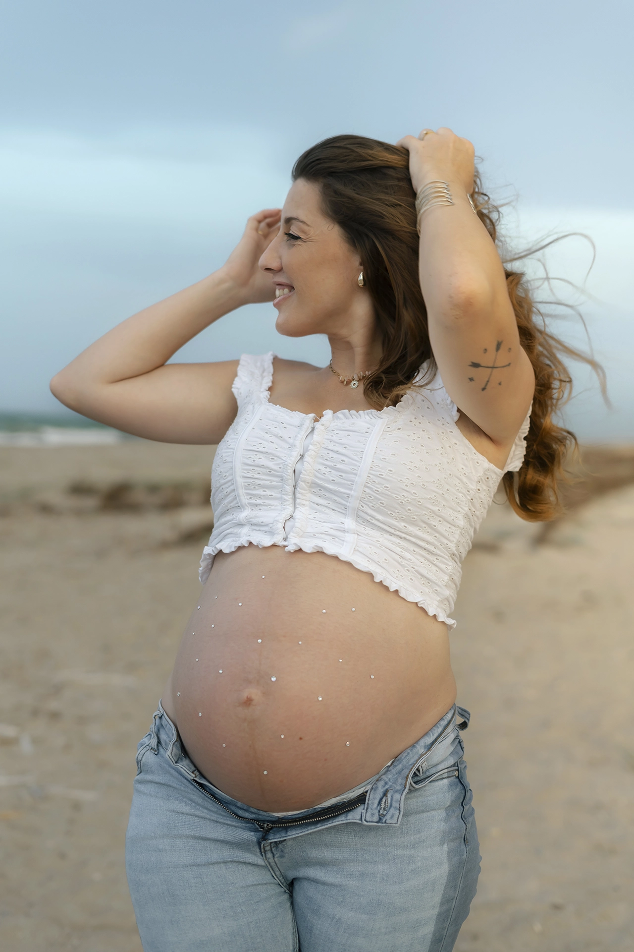 mujer embarazada en sesión de fotos en valencia en la playa cerca de El Saler. con la barriga decorada con brillos