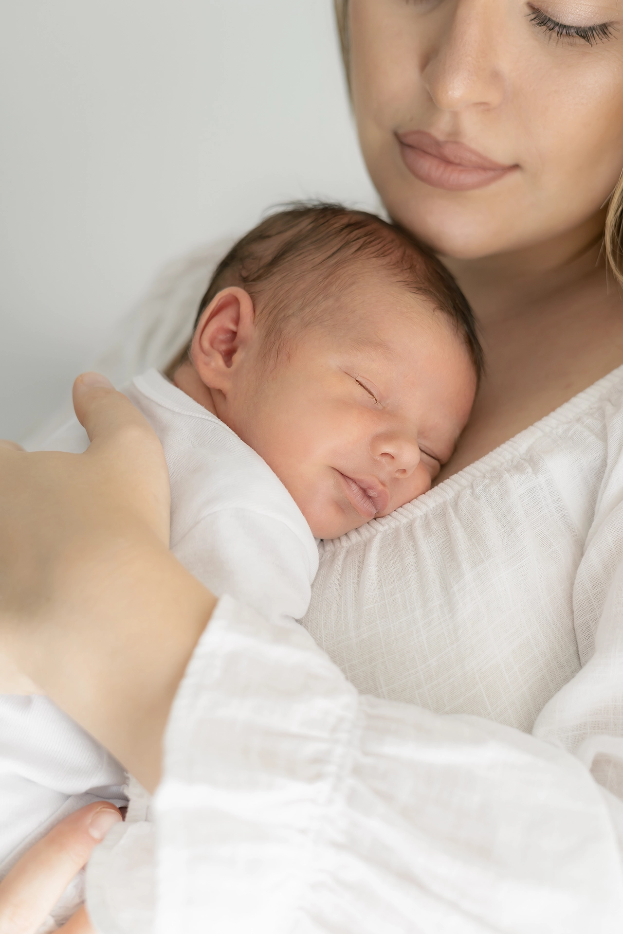 Fotografía de Recién nacido en estudio - Fotógrafo en Silla Valencia foto de madre junto a su hijo recien nacido, tonos blancos, sesión de fotos con calma y estilo minimalista