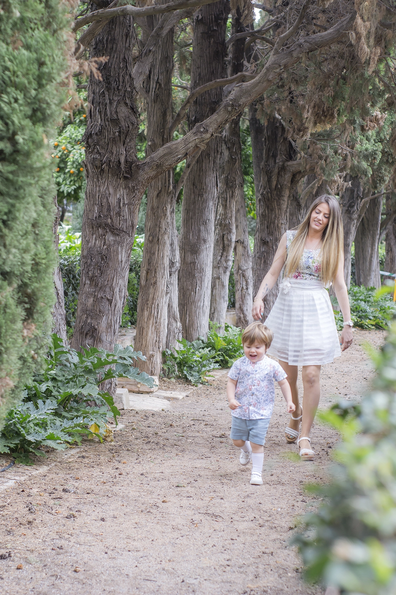 Reportaje de fotos en exterior para familias en Valencia Madre con su hijo jugando en un parque de valencia