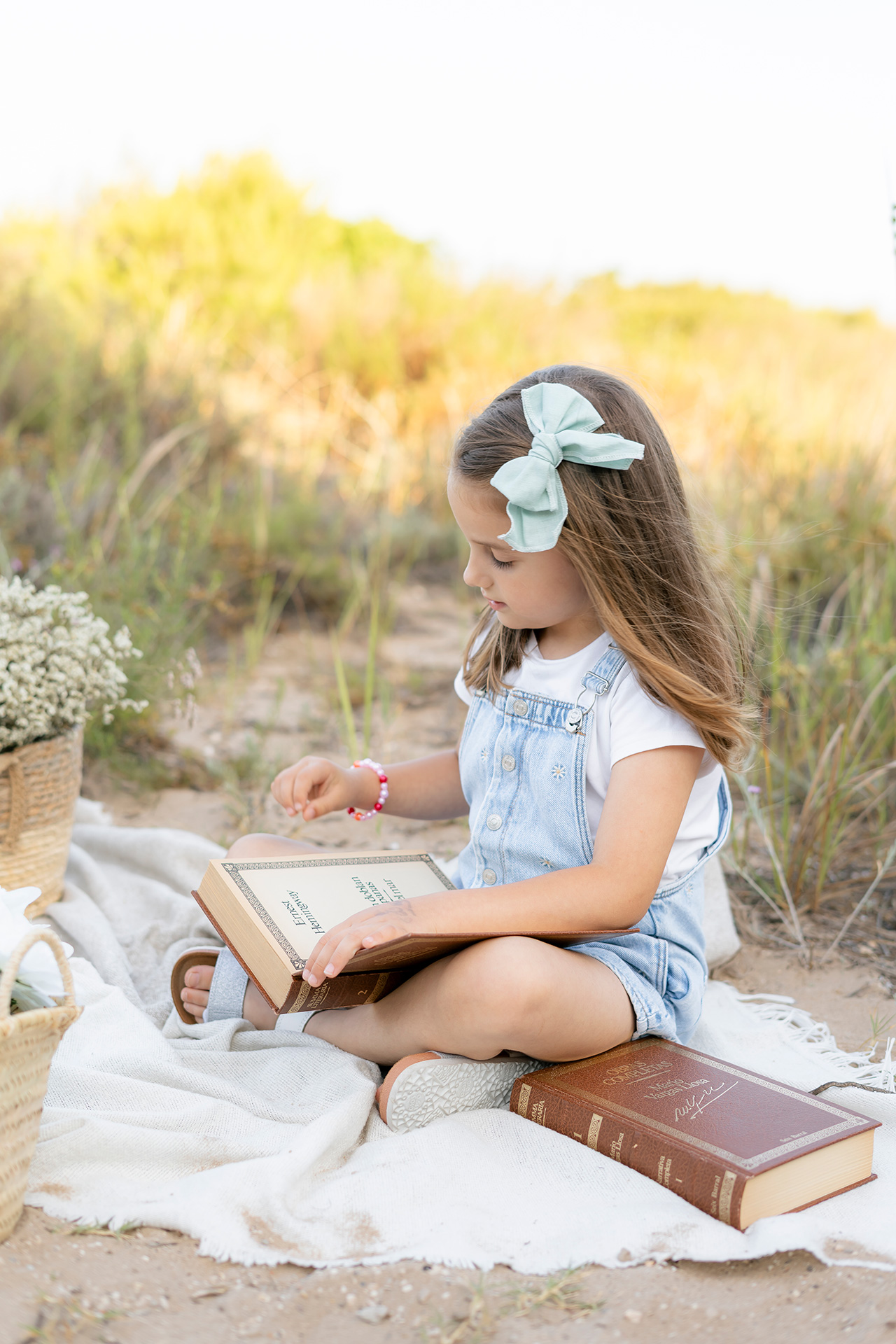 foto de una niña en la playa con decoración, flores, libros