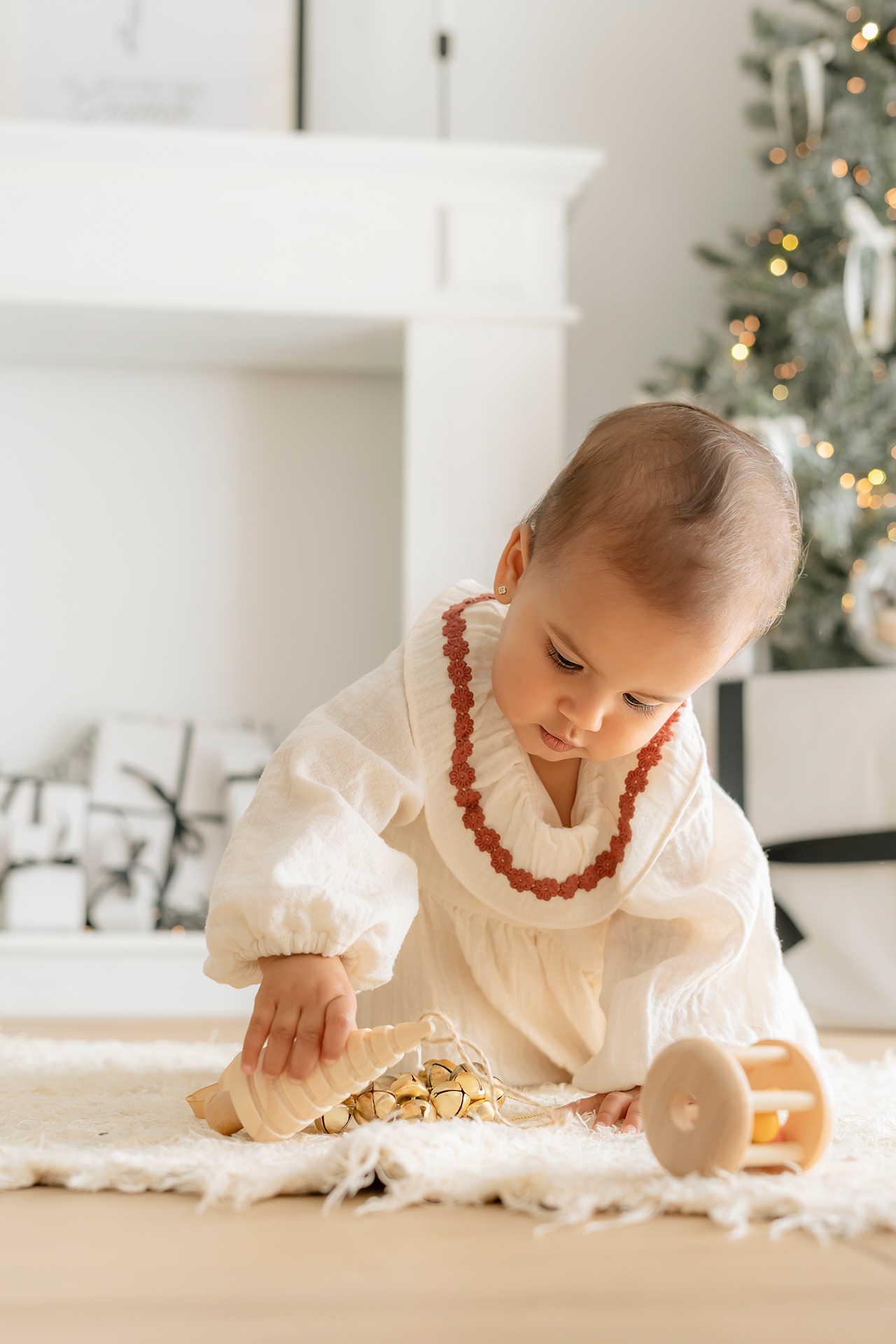 sesion fotos navidad - bebé jugando foto de niña bebe jugando en escenario de navidad, lleno de luces tonos cálidos y ropa de color beige