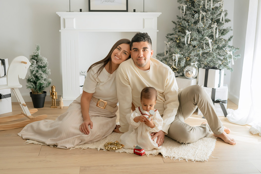 foto de familia en escenario de navidad en estudio, con tonos claros neutros y decoración moderna y minimalista. fotógrafo de familias en valencia