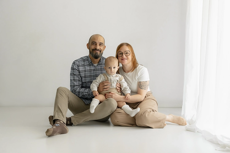 Retrato familiar de papás y su hijo sentados en el estudio fotográfico durante su sesión de cumpleaños