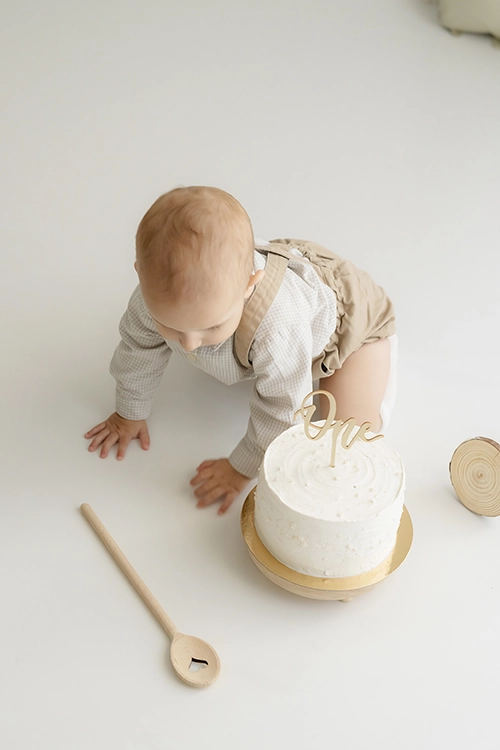 Bebé celebrando su primer cumpleaños comiendo una tarta en el estudio de fotografía.