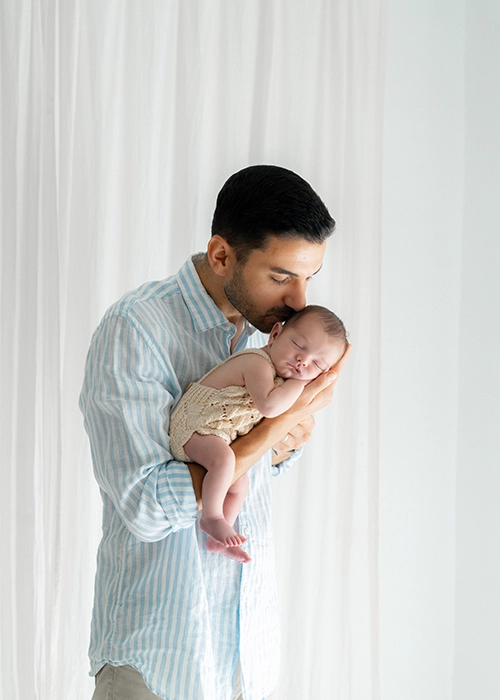 padre sosteniendo a bebe recien nacido en su brazo