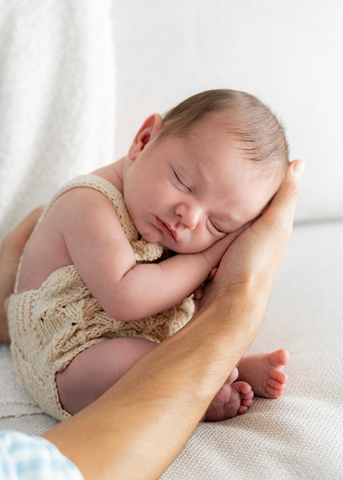 Foto de bebe recien  nacido dormido en las manos de su padre