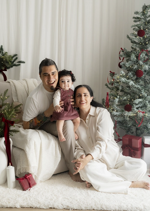 familia mirando a cámara sonriendo en escenario de navidad en tonos blancos y burdeos